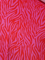 Red and pink tiger stripe patterned fabric with vibrant bold design and 150cm width