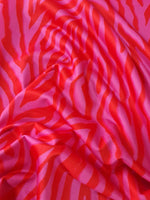 Close-up of red and pink tiger striped patterned fabric with visible texture and folds