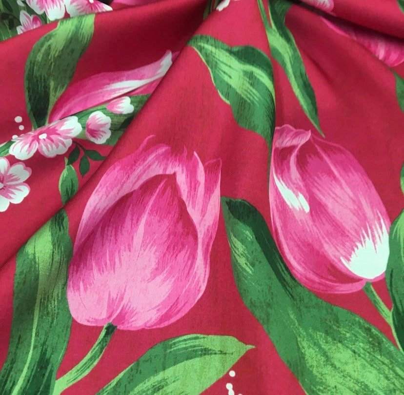 Pink tulip fabric with vibrant red background and green leaves for sewing and crafting projects