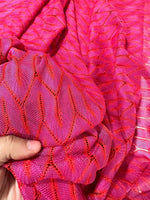 Close-up of pink and white chevron knit jersey fabric with zigzag pattern being held in hand