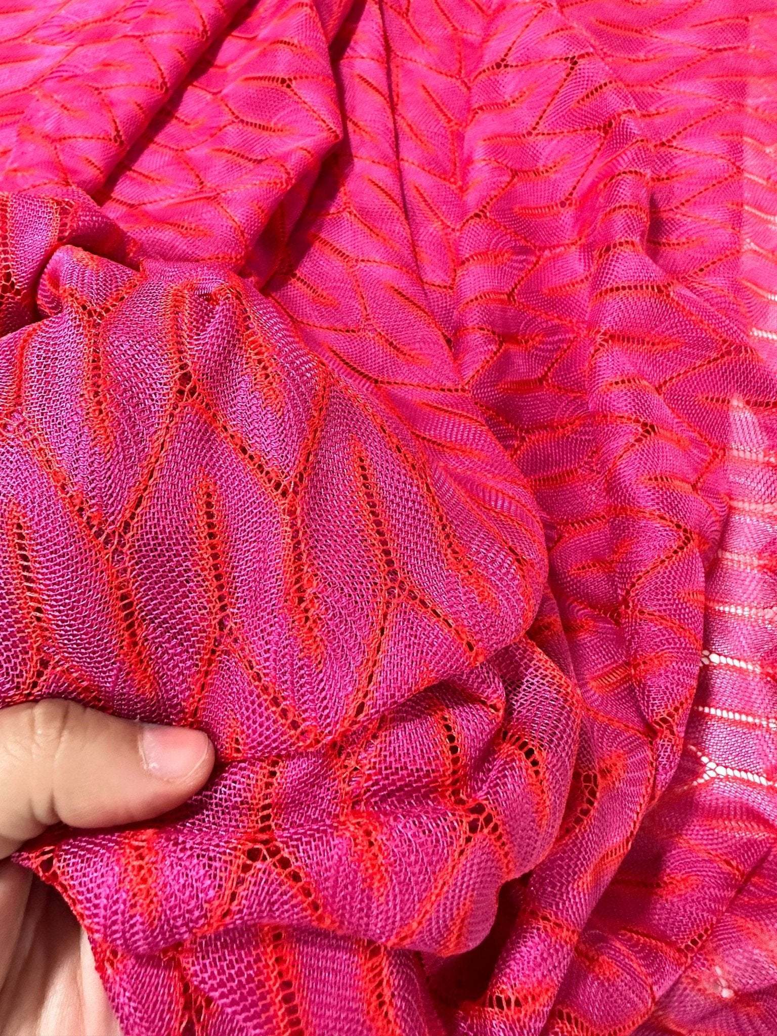 Close-up of pink and white chevron knit jersey fabric with zigzag pattern being held in hand