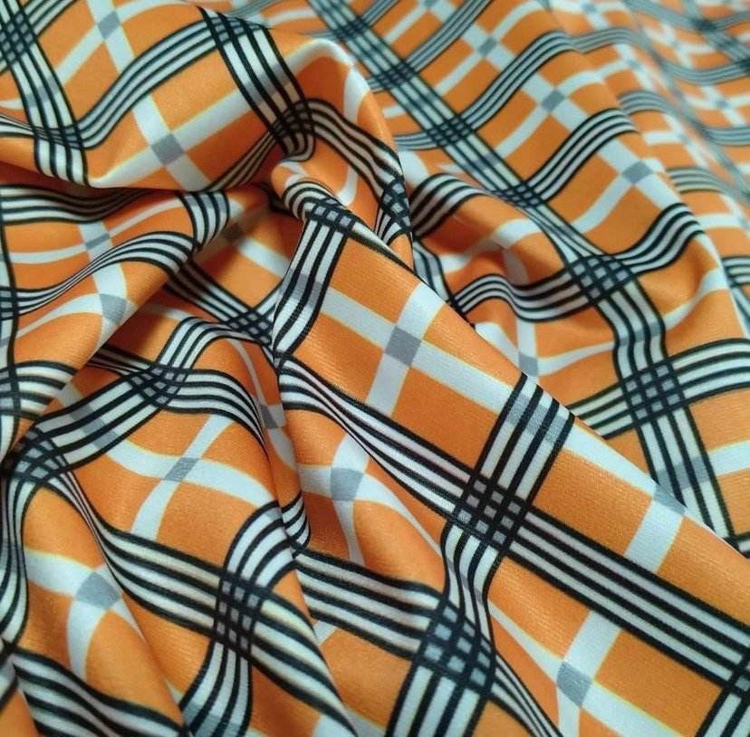Orange, black, and white 4-way stretch plaid fabric with a smooth texture and flexible drape
