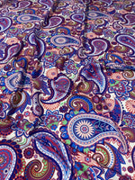 Purple paisley fabric with intricate multicolored digital print, ideal for upholstery and home decor projects.