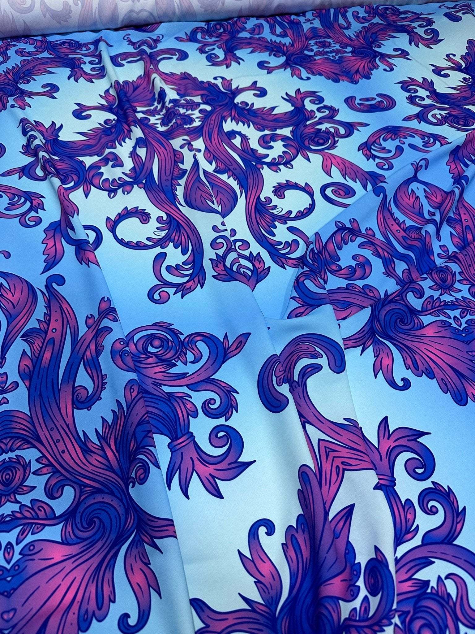 Purple and blue baroque pattern fabric with ornate floral and scroll design on a light blue background