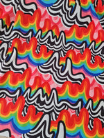 Close-up of vibrant rainbow abstract print fabric with wavy black and white patterns on a pink background