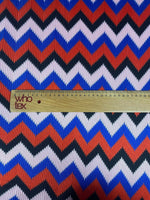 Close-up of red, blue, black zigzag chevron pattern knit fabric with measuring ruler for scale