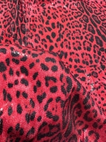 Close-up of red leopard sequin fabric with 2-way stretch and shiny black spots pattern