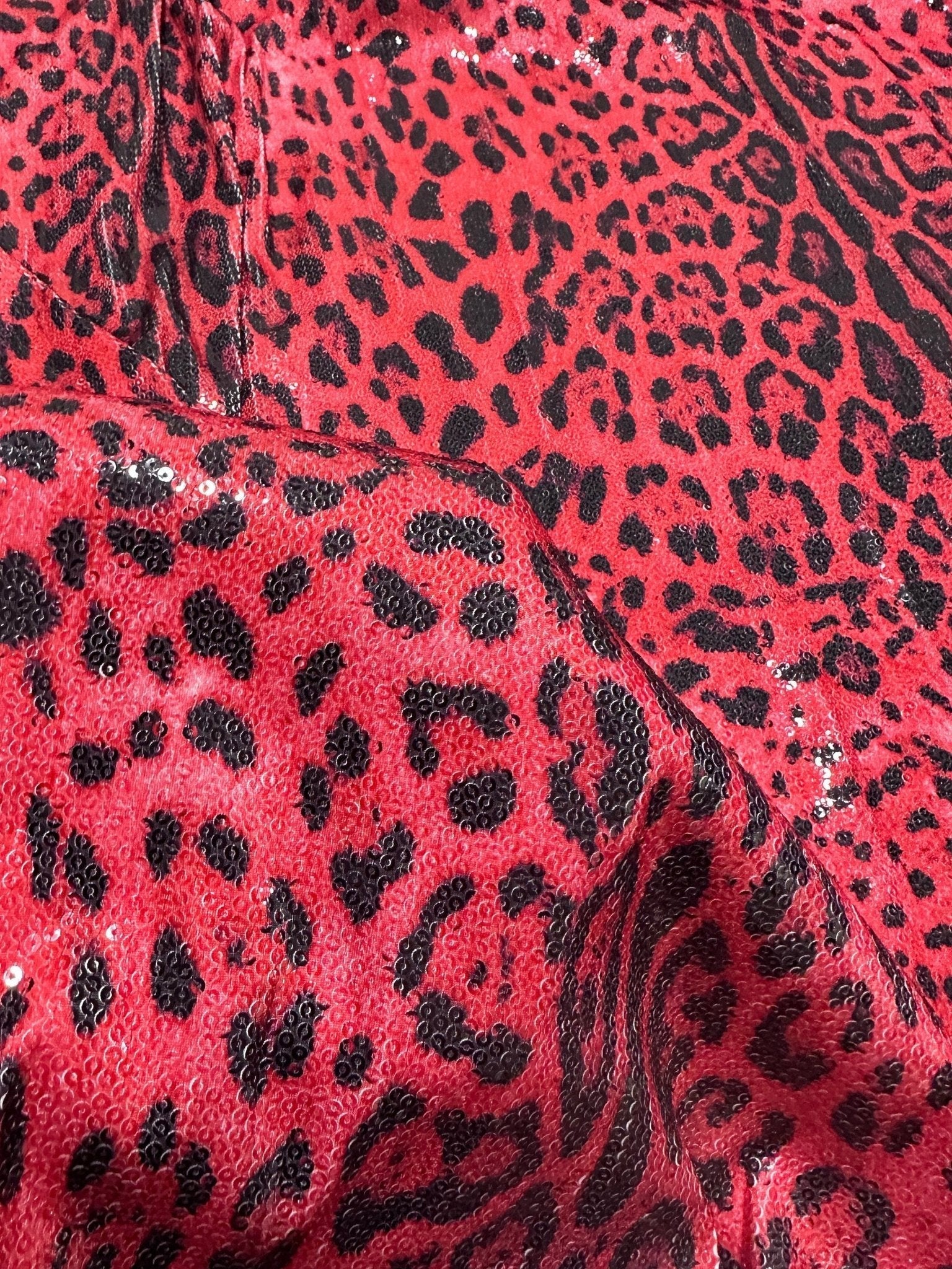 Close-up of red leopard sequin fabric with 2-way stretch and shiny black spots pattern
