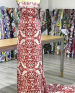 Red majolica pattern fabric with intricate floral design displayed on a mannequin in a fabric store.