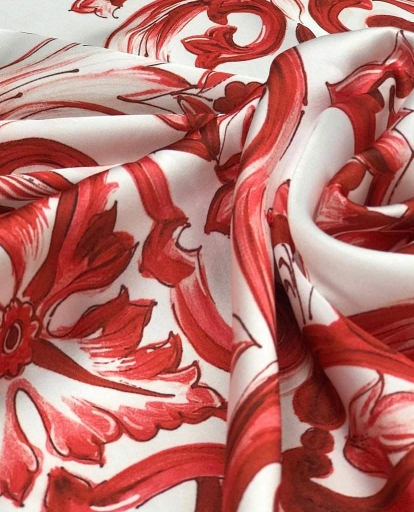 Close-up of red Majolica pattern floral fabric on white textile background