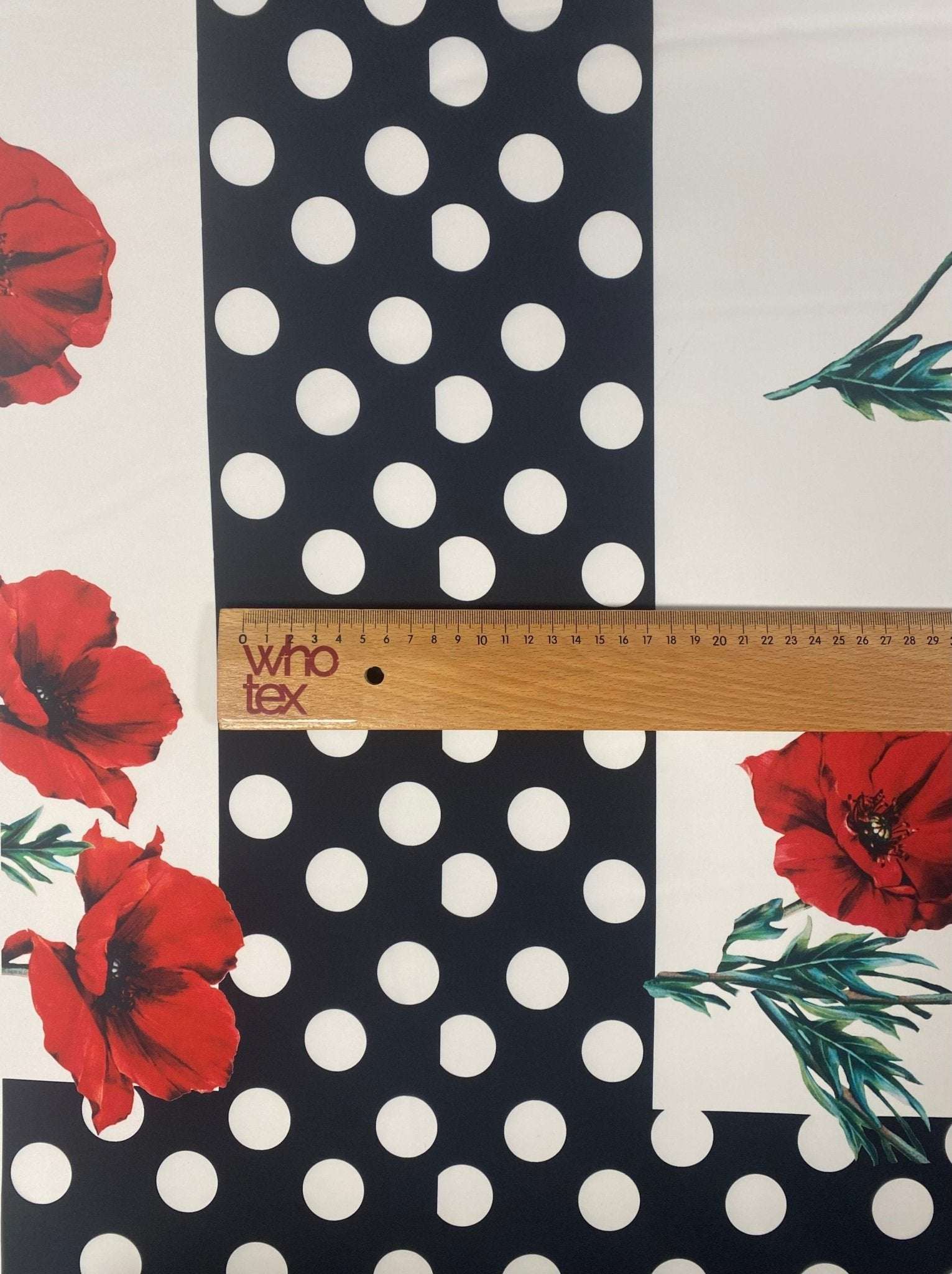 Red poppy floral fabric with black and white polka dot border and ruler showing fabric width