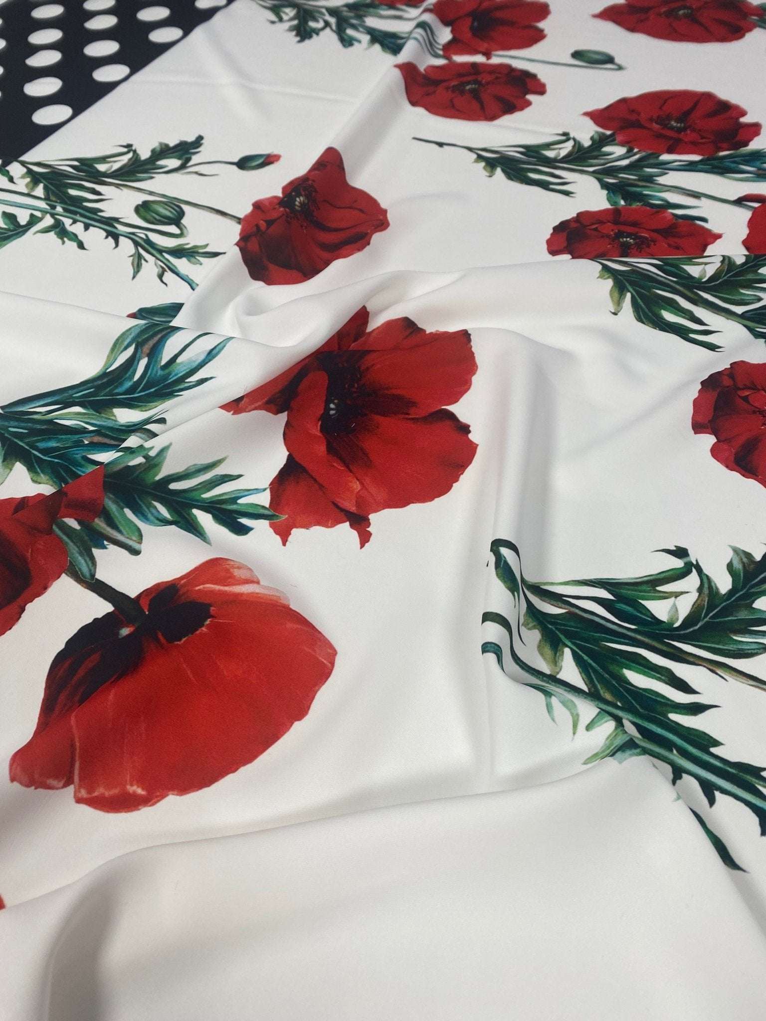 Red poppy floral fabric with green stems and polka dot border on white background