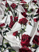 White fabric with vibrant red rose pattern and green leaves, soft and smooth textile for sewing projects