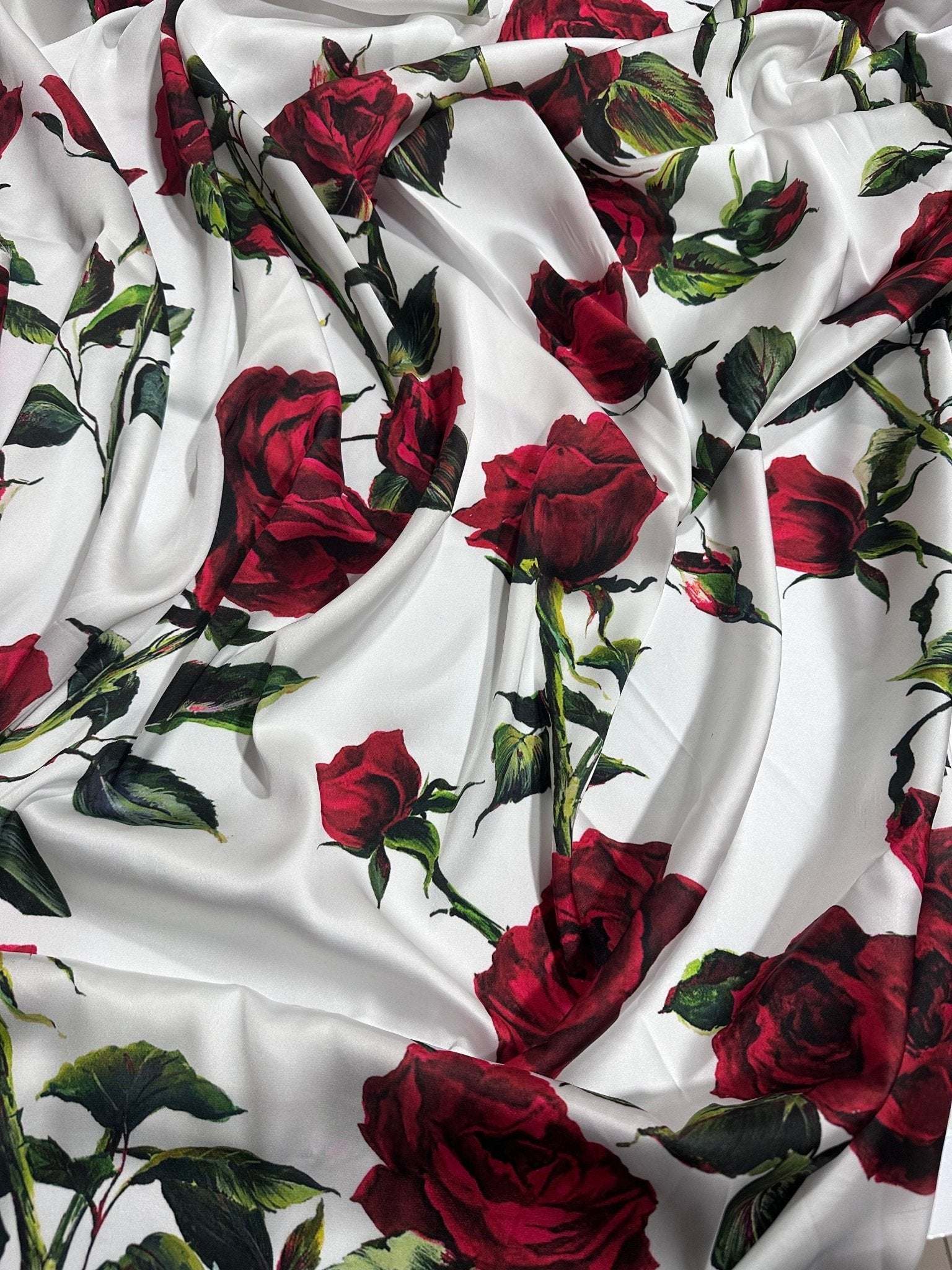 white fabric with vibrant red rose floral pattern and green leaves