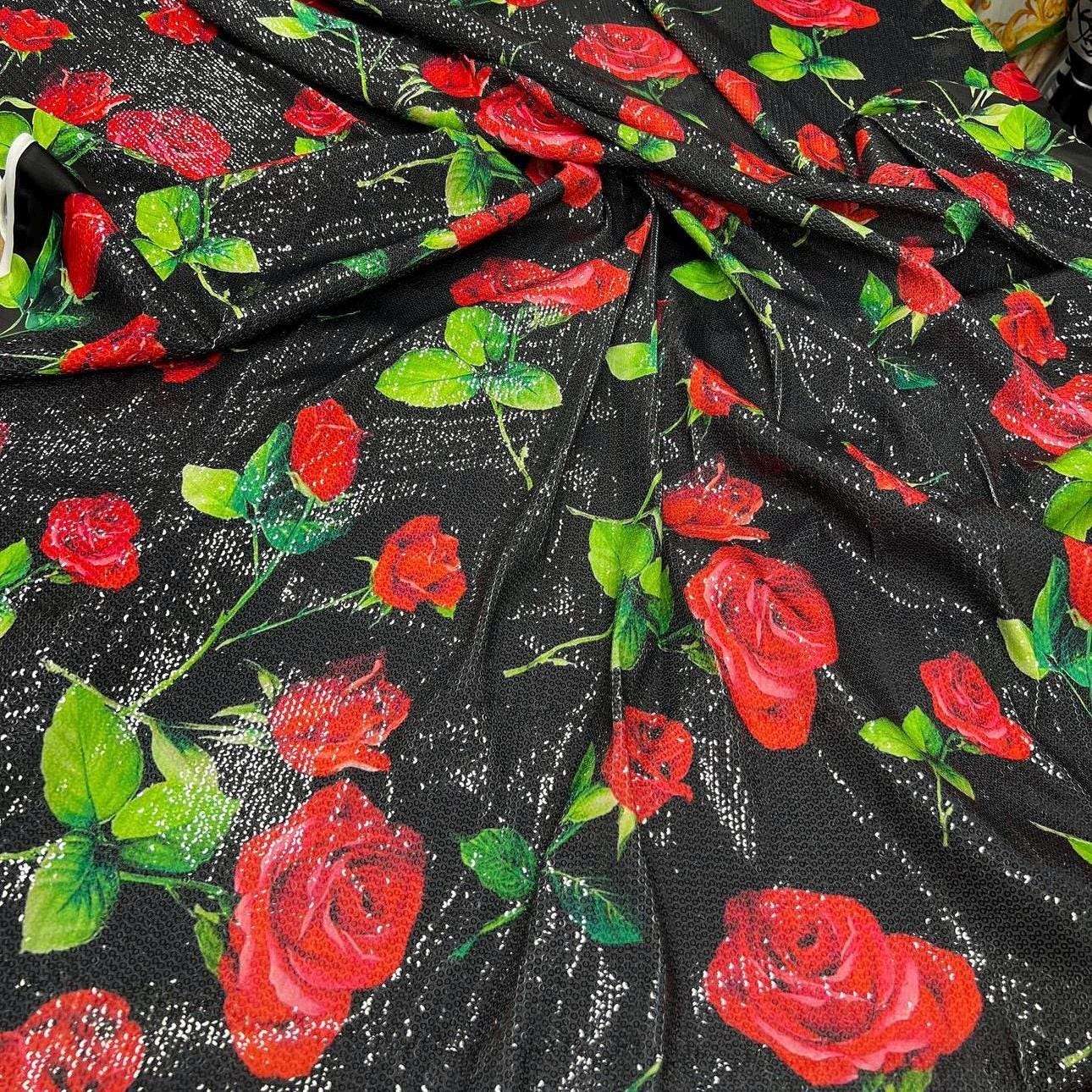Black fabric with red rose pattern and green leaves, covered in shimmering sequins with two-way stretch, ideal for elegant evening wear.