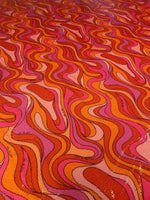 Retro wavy pattern sequin fabric in vibrant red, pink, and orange tones with 2-way stretch for fashion apparel.