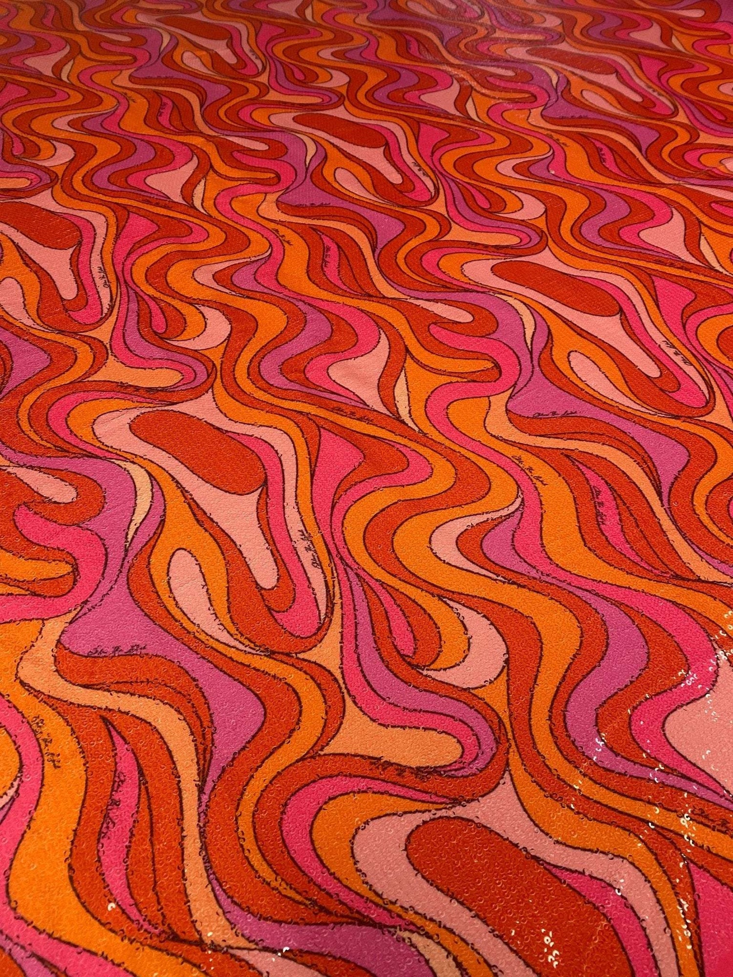 Retro wavy pattern sequin fabric in vibrant red, pink, and orange tones with 2-way stretch for fashion apparel.