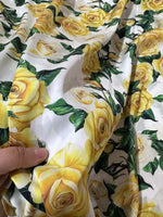 Yellow floral rose pattern fabric with green leaves held in hand for sewing and crafting projects