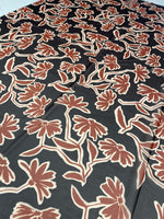 Rust red floral print fabric with black background and vibrant flower design