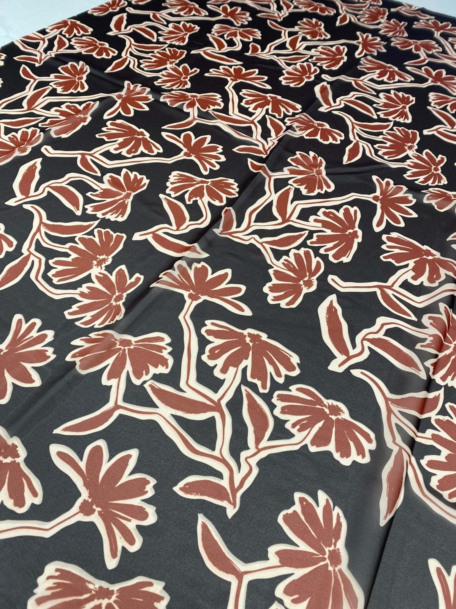 Rust red floral print fabric with black background and vibrant flower design