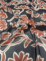 Rust red floral print fabric with black background and wide floral patterns