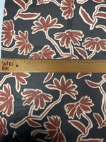 rust red floral print fabric with large flowers on black background with measuring ruler for scale