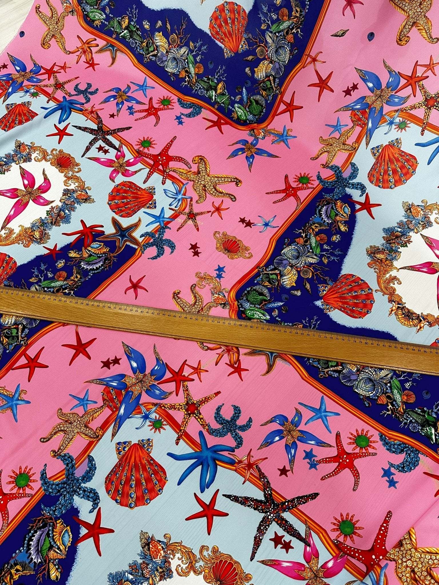 Bright coastal sea shell fabric with starfish and seashell patterns on pink and blue background