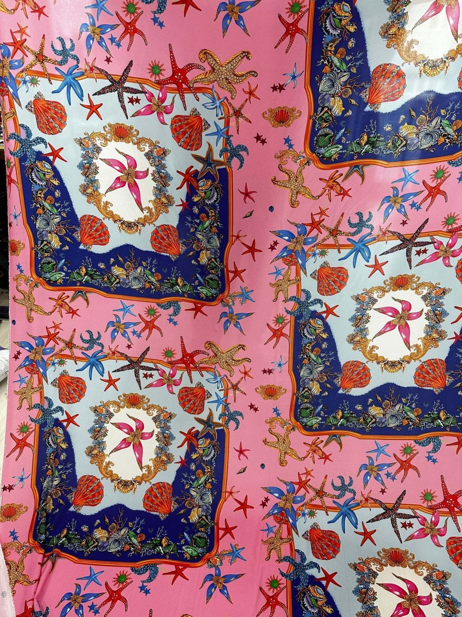 Coastal sea shell fabric with starfish and seashell patterns on pink background