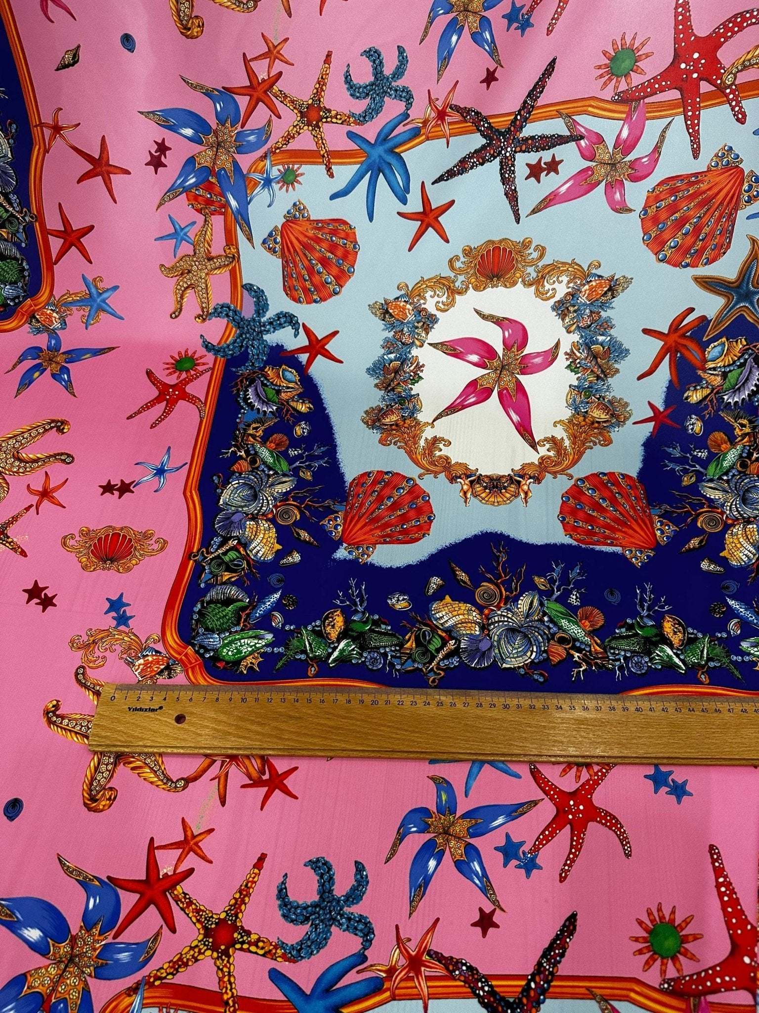 Coastal sea shell fabric with colorful starfish and shell patterns on pink and blue background