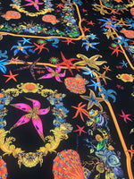 Black fabric with vibrant pink starfish and colorful sea shell pattern for crafting and apparel