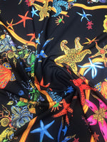 Black fabric with colorful pink and blue starfish sea shell pattern for crafting and apparel