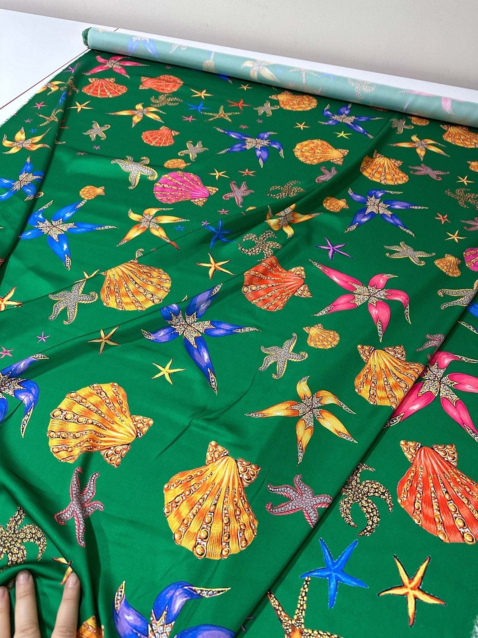 Green fabric with colorful sea shell and starfish pattern for coastal decor and crafting projects
