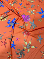 Orange fabric with colorful oyster sea shell and starfish pattern textile
