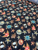 Sea shell and starfish pattern fabric with vibrant coastal-themed design on dark background, featuring turtles, crabs, and coral motifs.