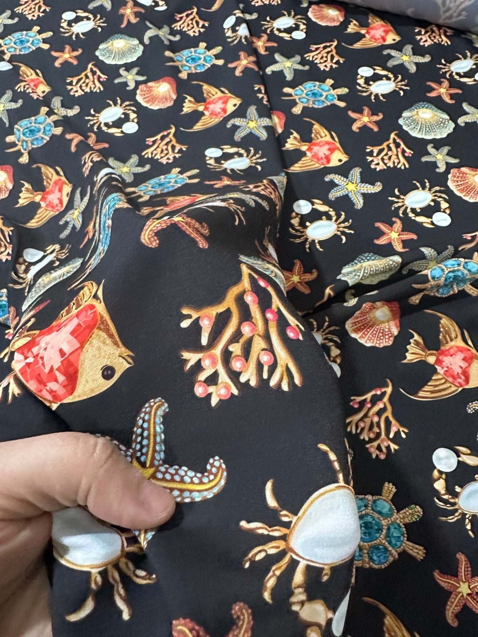 Fabric with sea shell and starfish pattern on black background for beach-themed crafts and decor