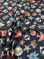 Black fabric with colorful sea shell, starfish, crab, coral, and turtle pattern