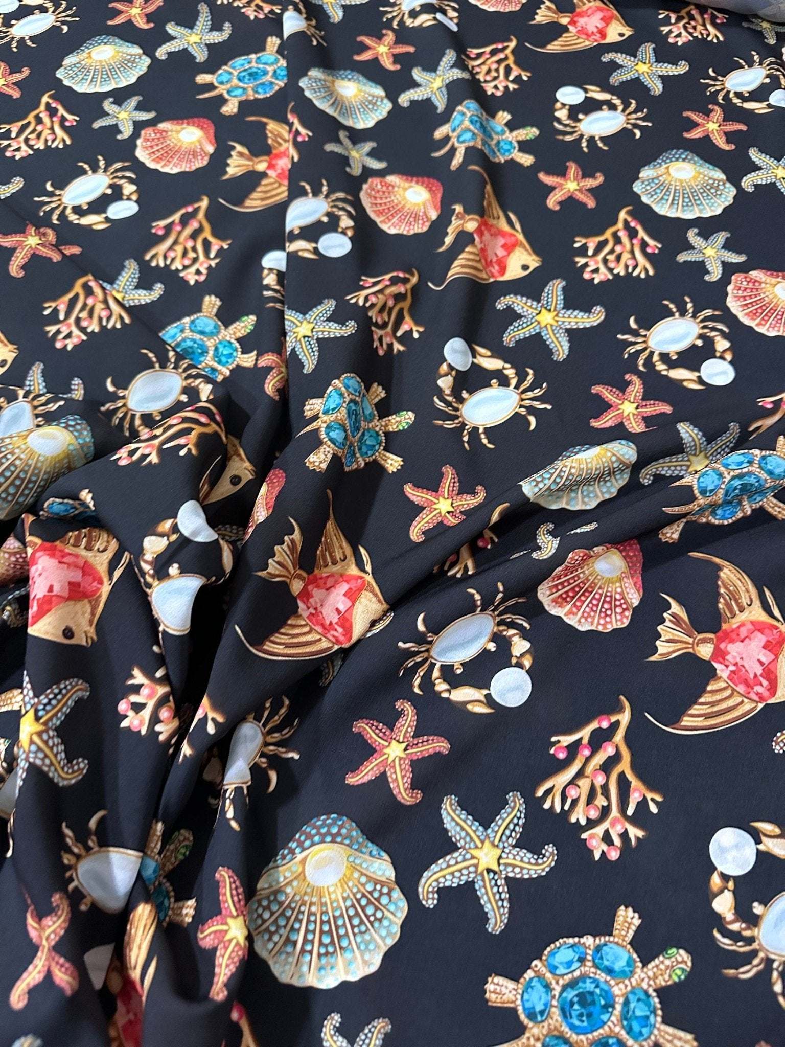 Black fabric with colorful sea shell, starfish, crab, coral, and turtle pattern