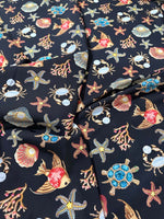 Black fabric with colorful sea shell, starfish, crab, fish, coral, and turtle pattern design