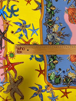 Close-up of colorful sea shells and starfish patterned fabric with a measuring ruler on yellow and blue background, Sea Shells Starfish Fabric design.