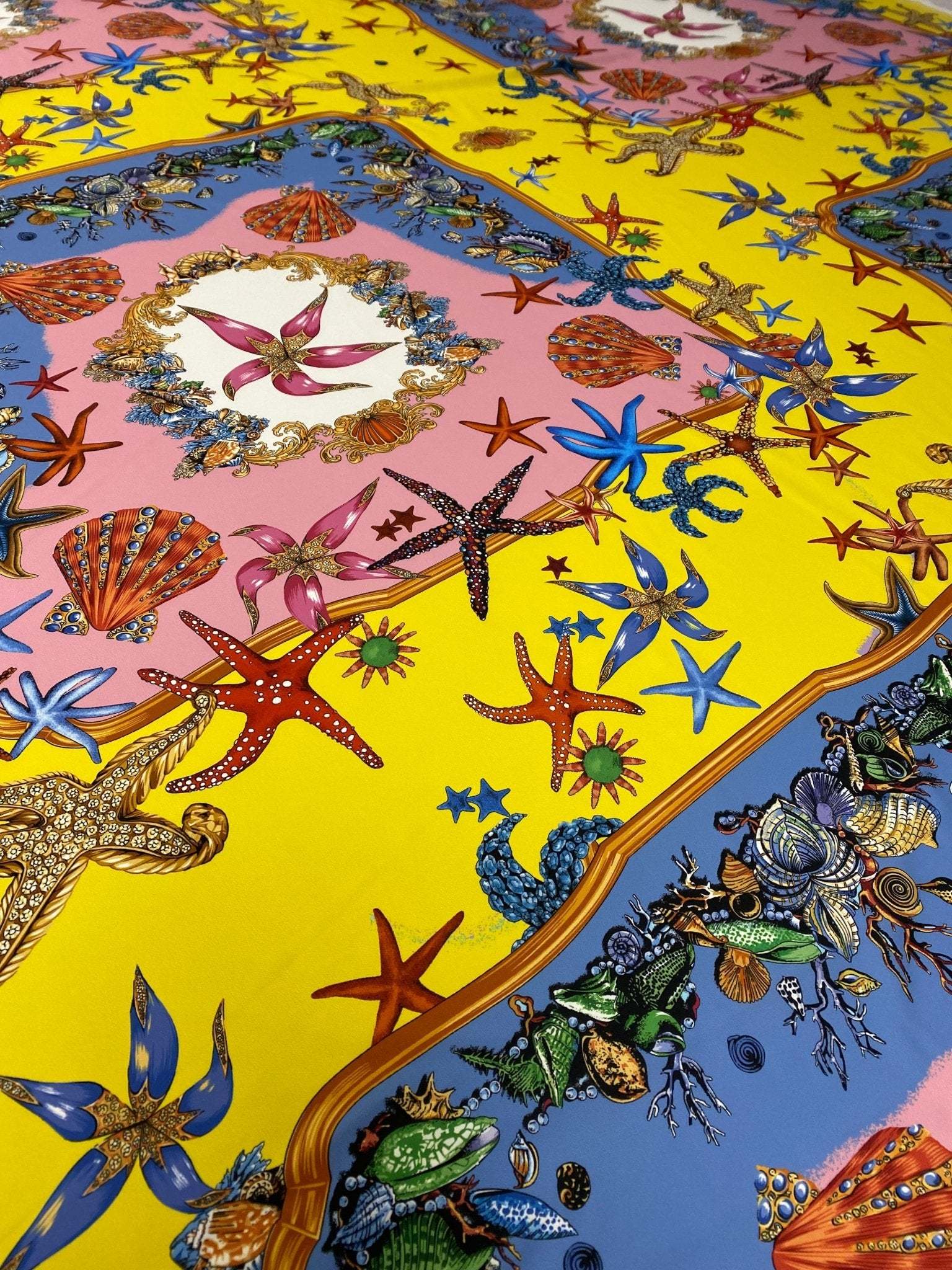 Bright coastal fabric with sea shells and starfish pattern in yellow, pink, and blue colors