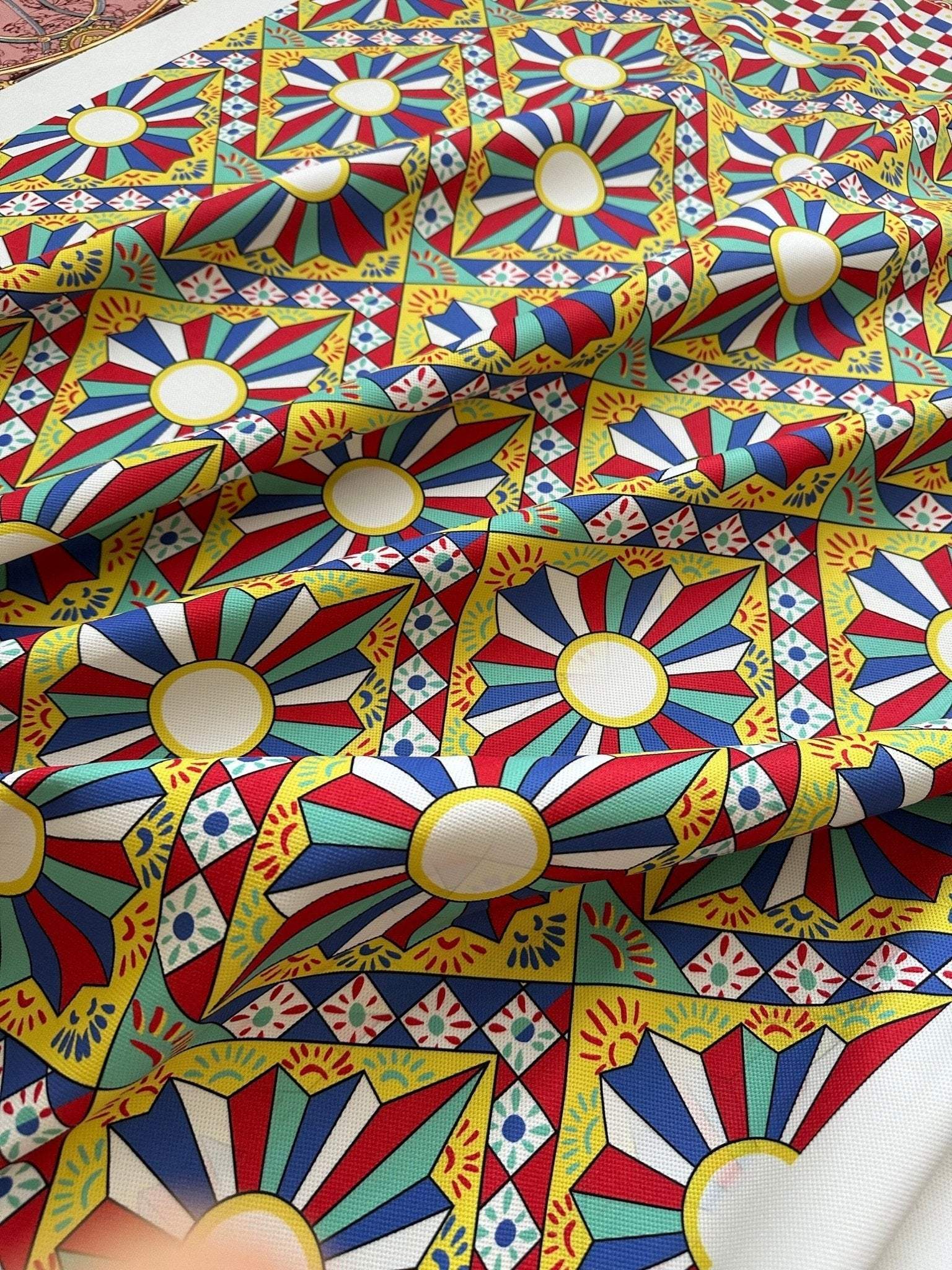 Patterned Sicilian Caretto Upholstery Fabric with vibrant geometric and sunburst design in red, blue, yellow, and green colors.