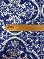 Close-up of blue and white Sicilian print fabric with intricate floral and geometric patterns and a wooden ruler for scale