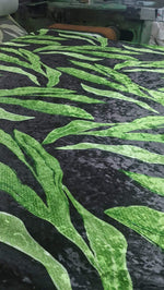 Silky velvet fabric with green leaf pattern on black background, lightweight lycra blend, smooth and wrinkle-free material for clothing and home decor