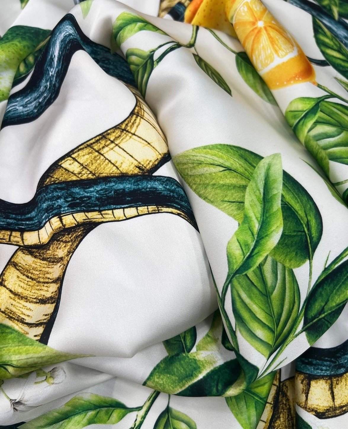 Close-up of Snake and Lemon Fabric with snake, lemon slices, and green leaf prints on white background.