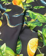 Close-up of Snake and Lemon Fabric with snake, lemon, and green leaf print on dark background