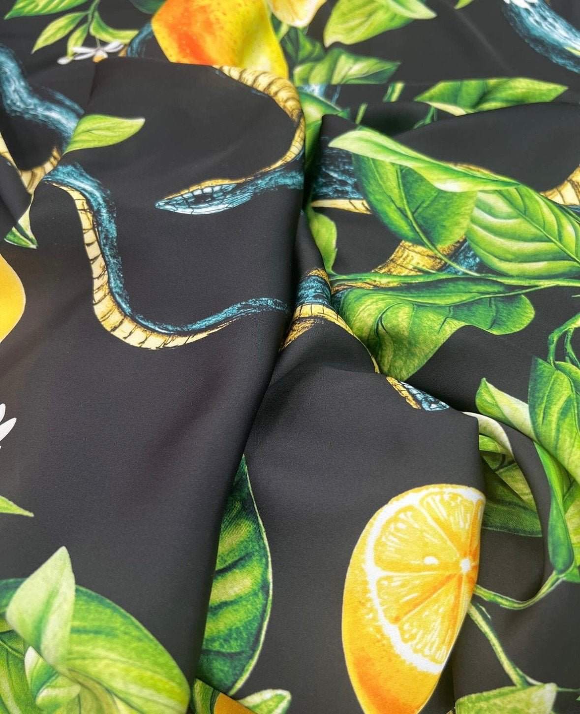 Close-up of Snake and Lemon Fabric with snake, lemon, and green leaf print on dark background