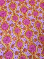 Pink geometric pattern floral spandex fabric with orange and purple floral designs and wavy lines