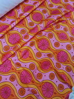 Pink geometric pattern floral spandex fabric with vibrant orange and pink floral designs and wavy lines