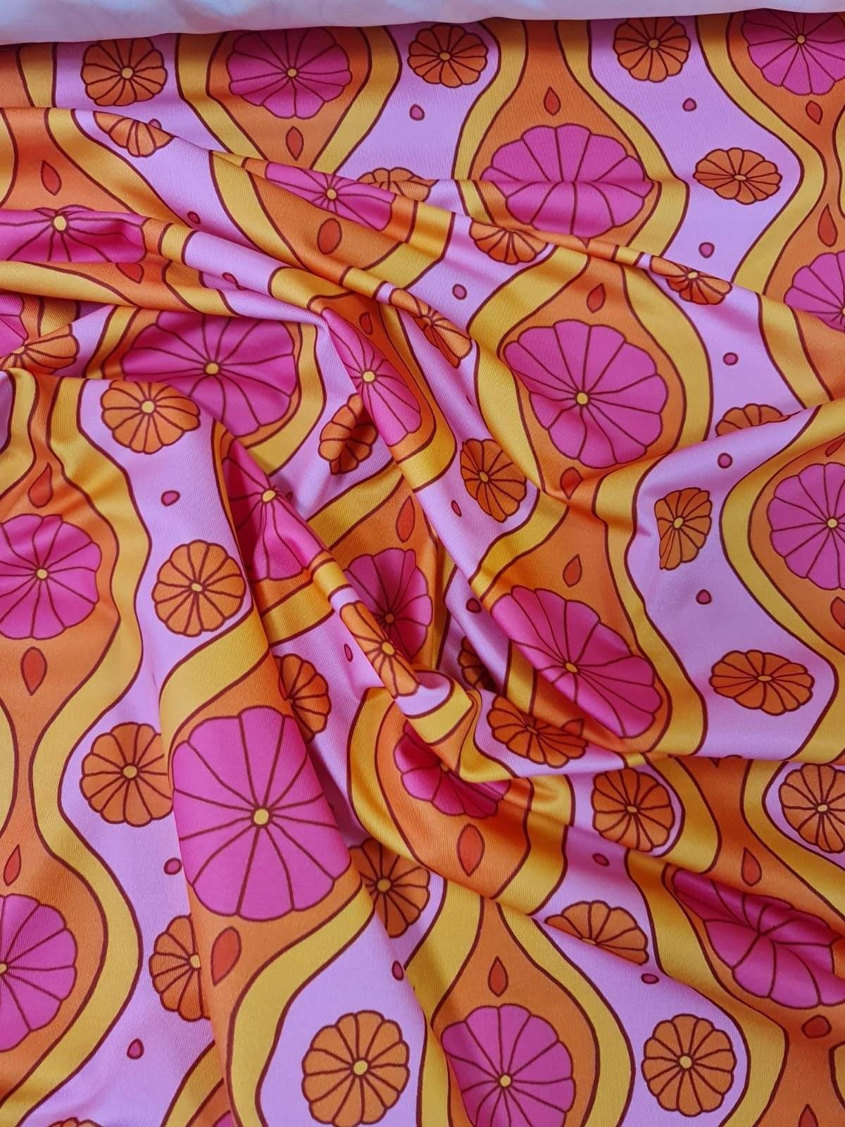 Pink geometric pattern floral spandex fabric with orange and yellow floral designs on a pink background