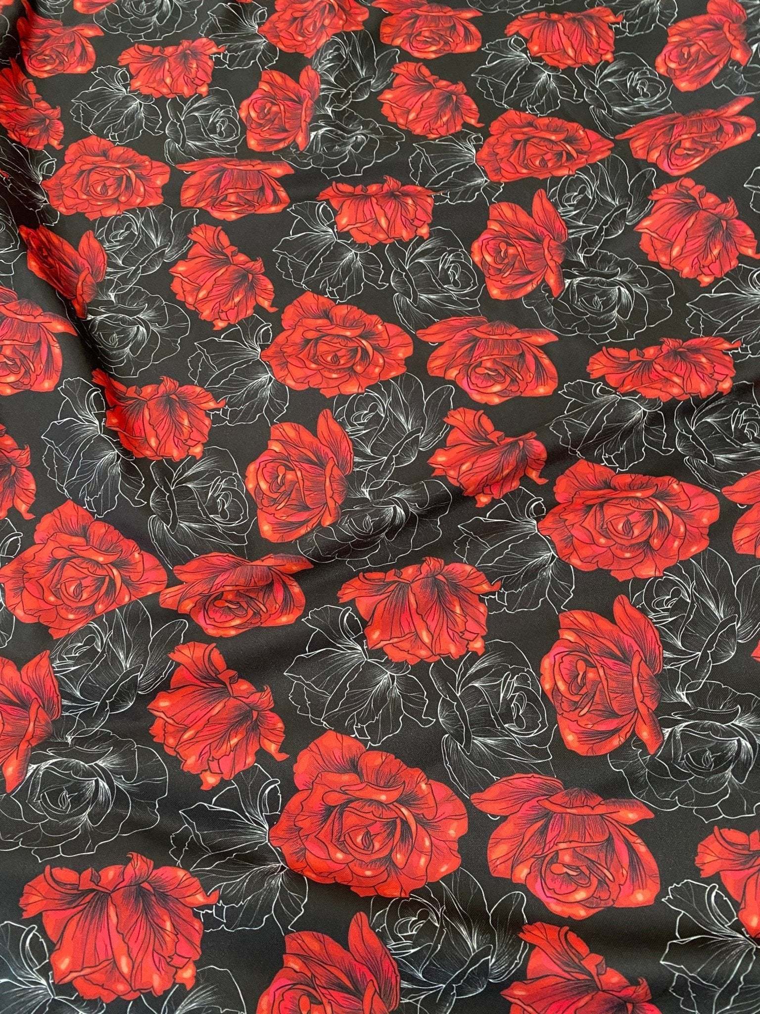 Elegant red rose patterned spandex fabric on black background with floral design and stretch texture